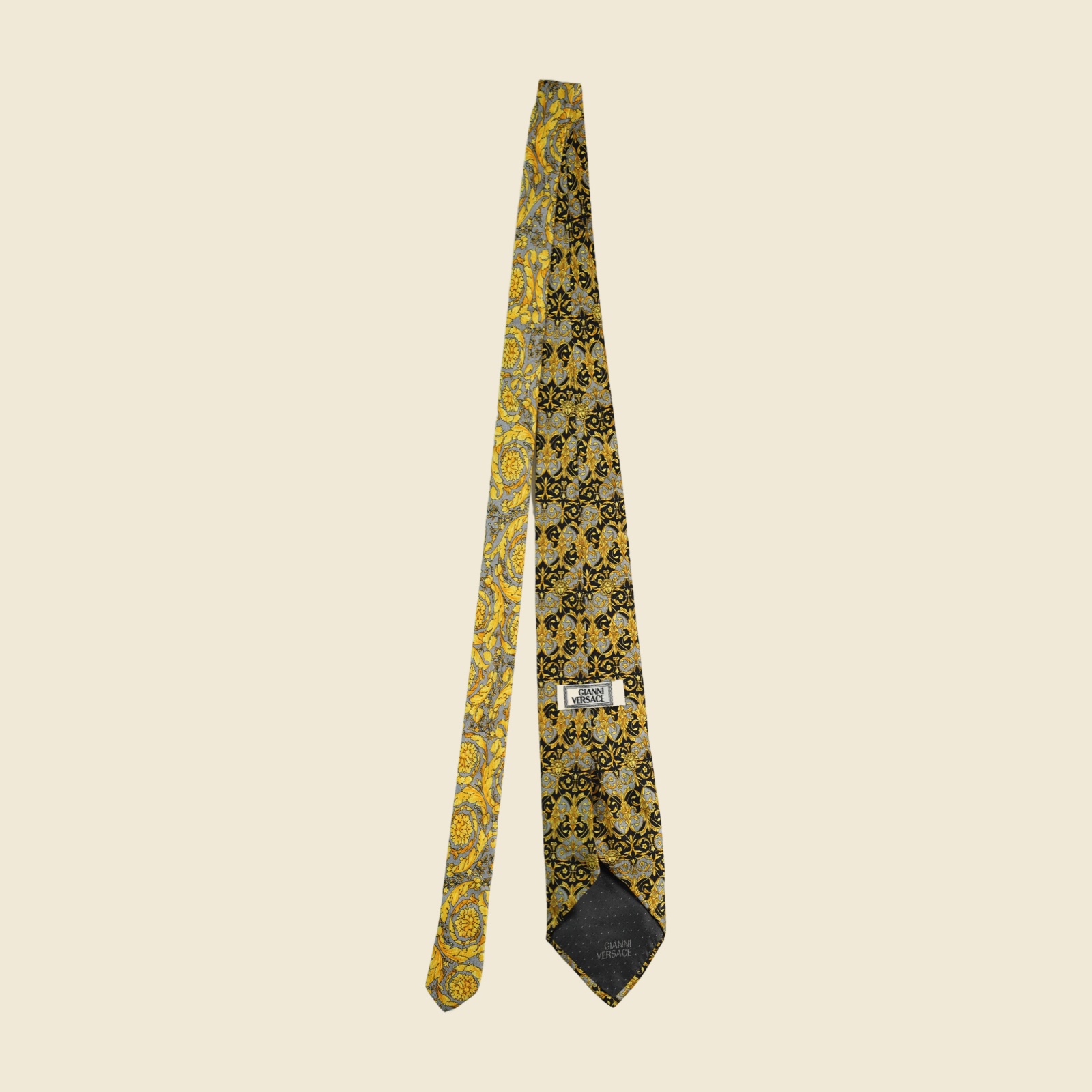 Cravatta Gianni Versace barocca a pannello, volute e mascheroni in oro su fondo nero e grigio argento, vista frontale su fondo neutro — vista 3