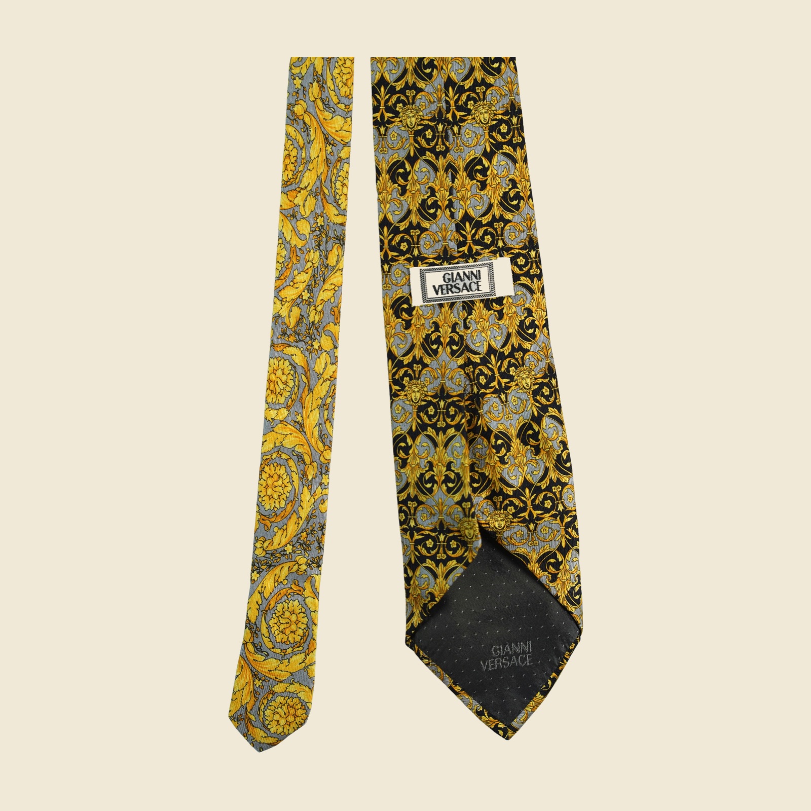 Cravatta Gianni Versace barocca a pannello, volute e mascheroni in oro su fondo nero e grigio argento, vista frontale su fondo neutro — vista 4