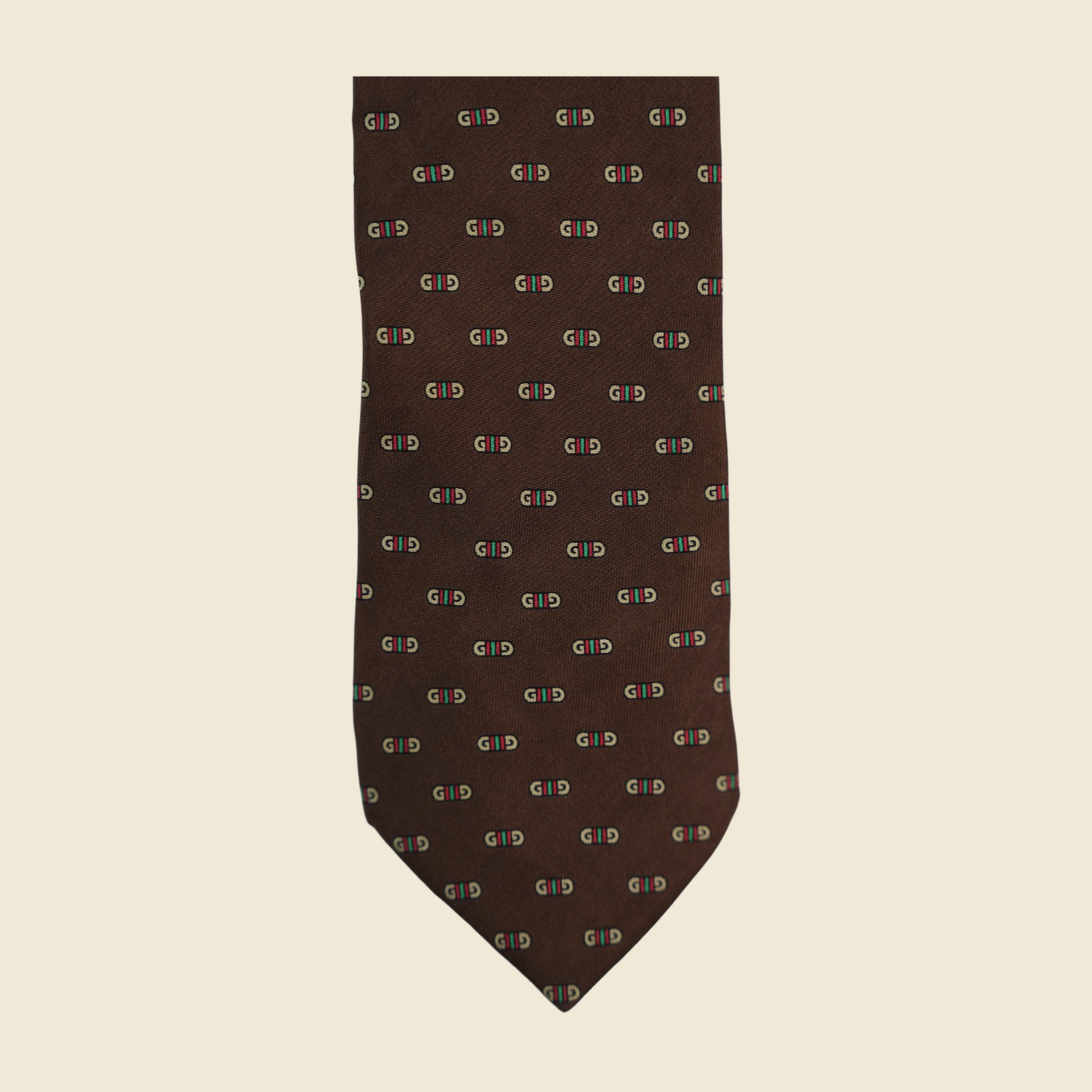Cravatta Gucci in seta jacquard marrone testa di moro, con doppia G avorio e banda Web rosso e verde, vista frontale su fondo neutro