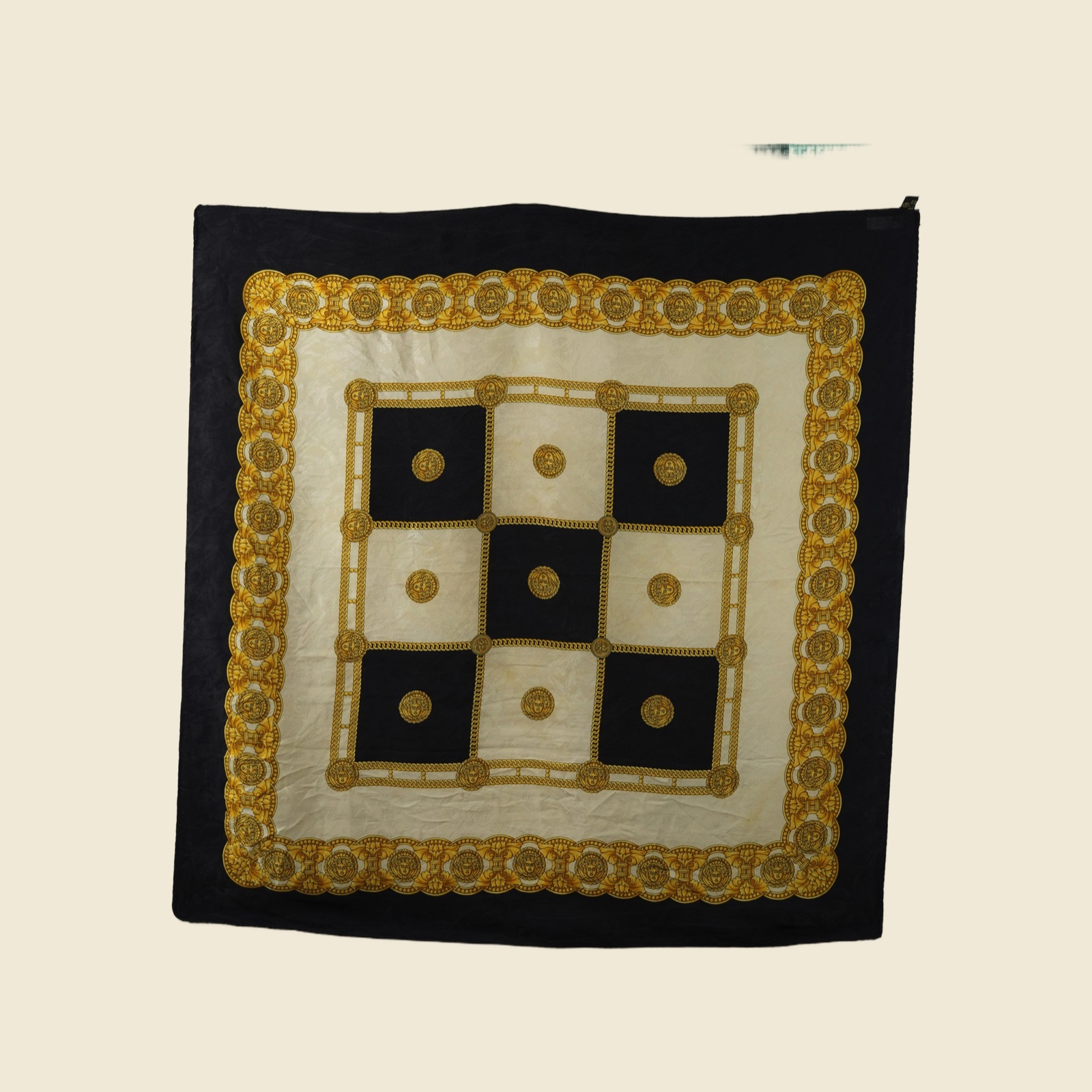 Foulard quadrato in seta disteso, scacchiera di riquadri neri e avorio con catena groumette dorata e medaglioni a testa coronata
