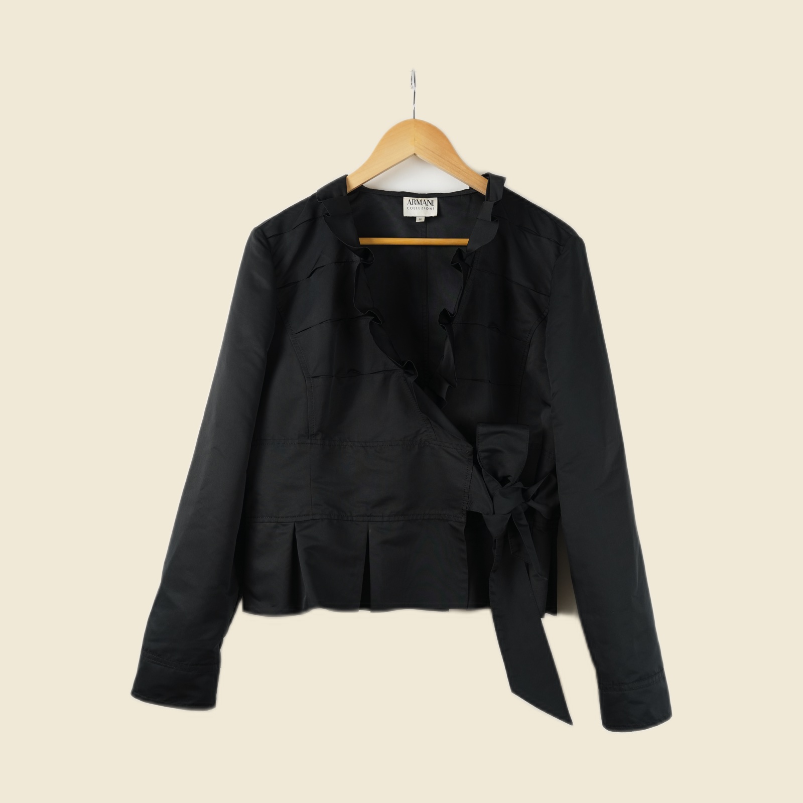 Blusa Armani Collezioni in poliestere nero lucido, incrocio annodato a fiocco sul fianco, balza plissé sul fondo