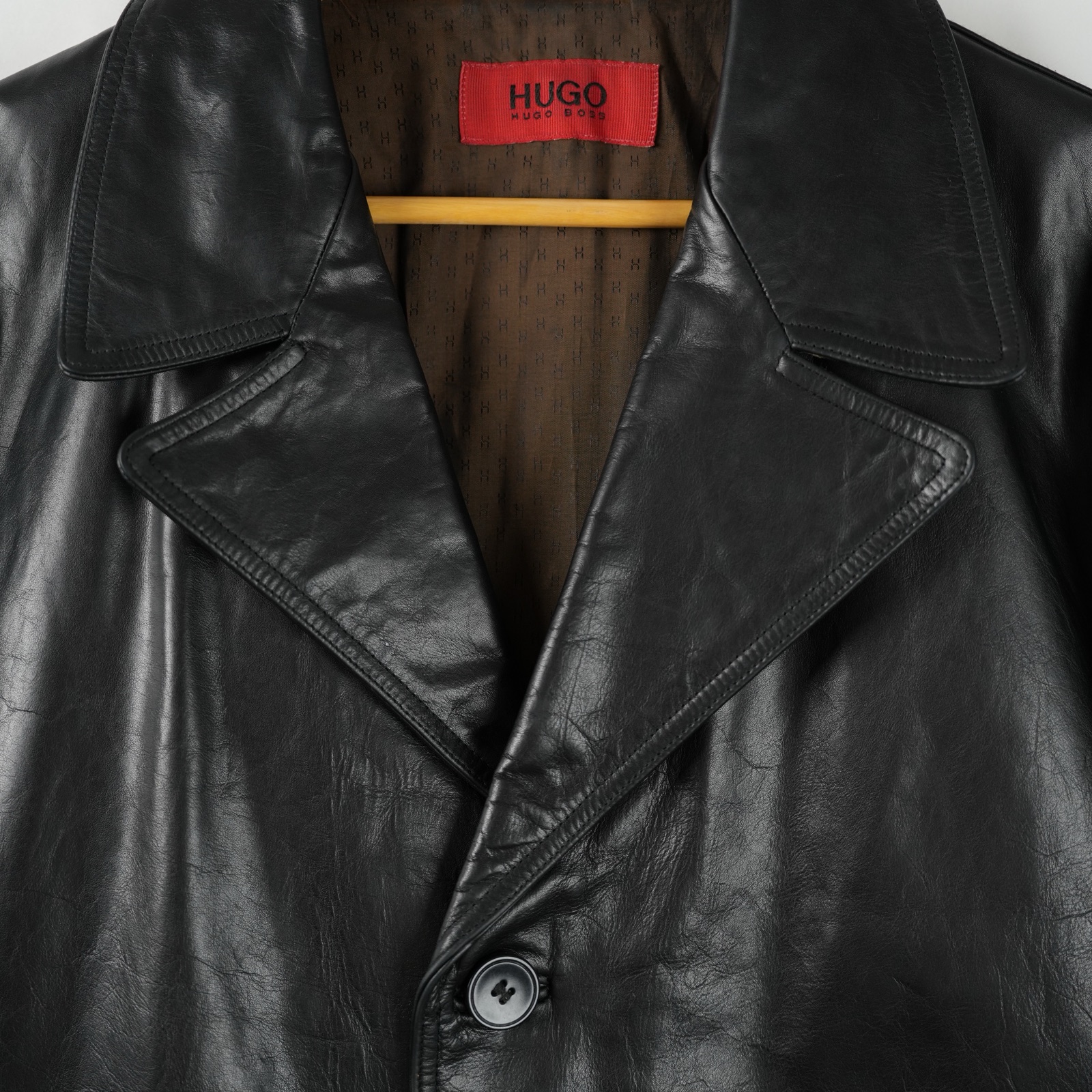 Giaccone Hugo Boss in pelle nera con tre bottoni e due tasche applicate, appeso su gruccia — vista 2