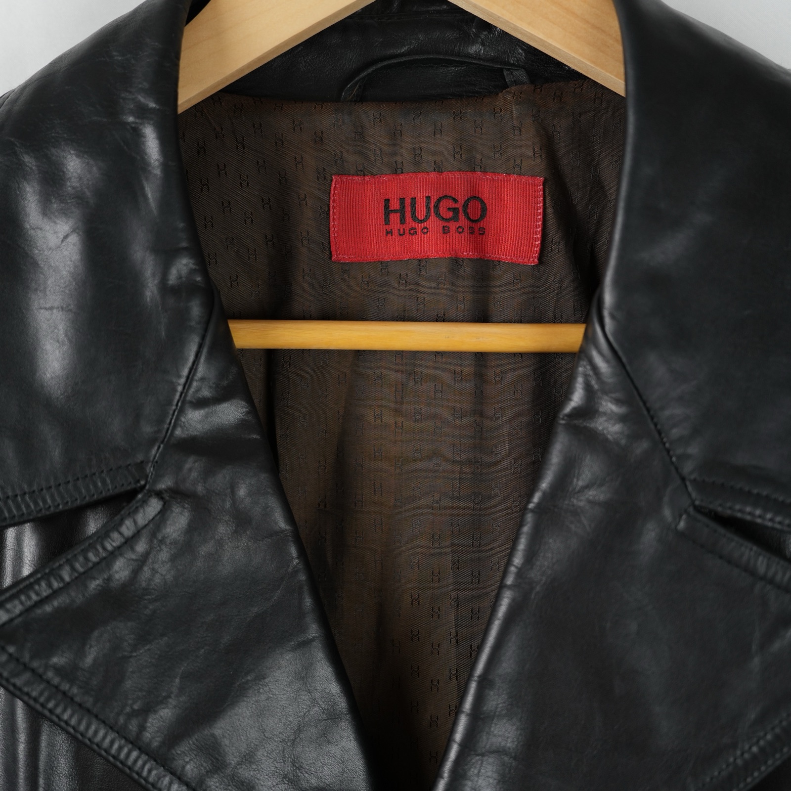 Giaccone Hugo Boss in pelle nera con tre bottoni e due tasche applicate, appeso su gruccia — vista 3