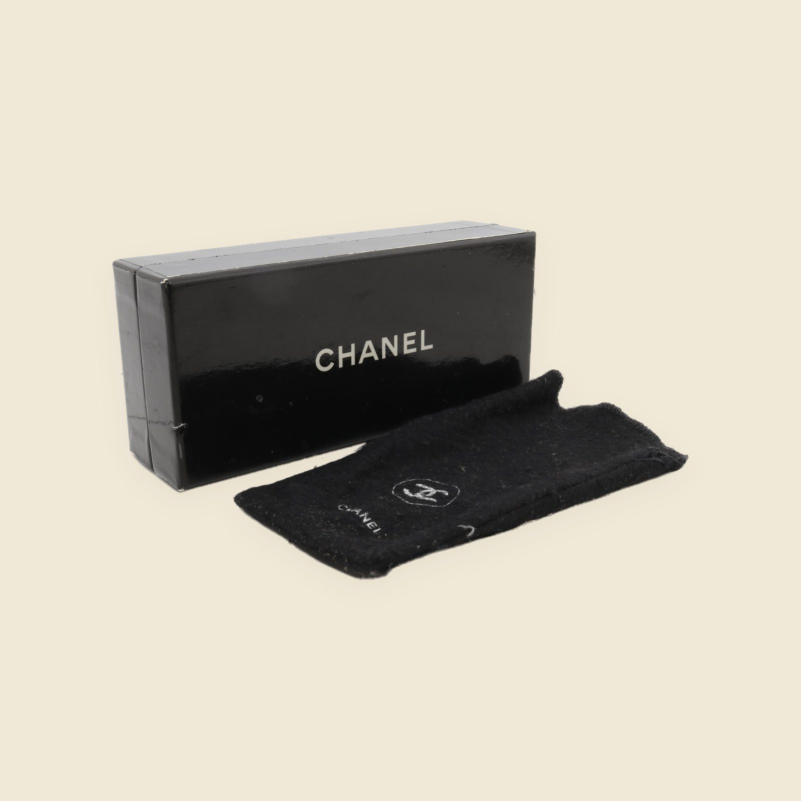 Occhiali da sole Chanel con montatura ovale nera lucida, lenti grigie e doppia C dorata sull'asta, su piano bianco — vista 3