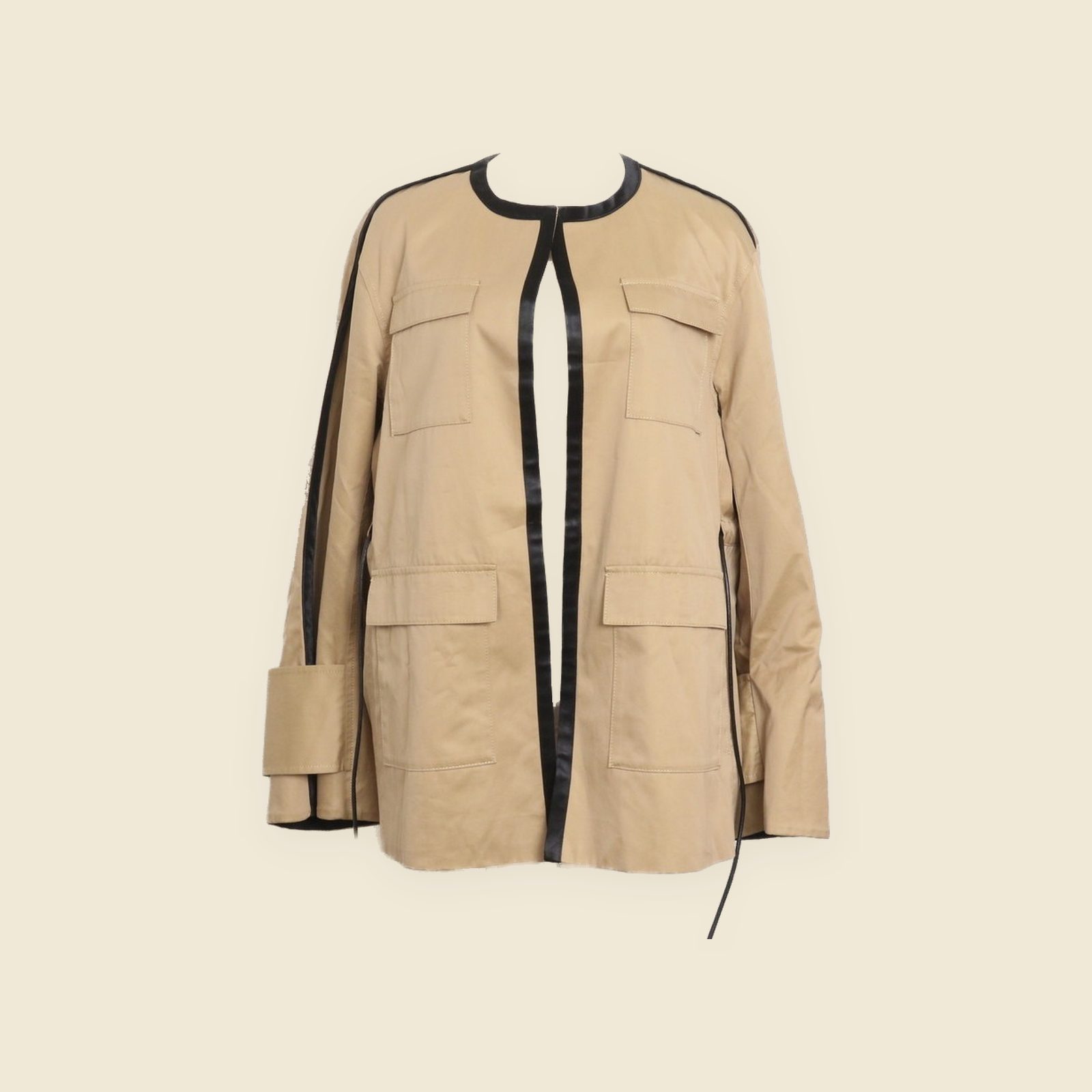 Giacca Cinoh beige senza collo su manichino, con profili neri al girocollo e lungo l'apertura e quattro tasche con pattina