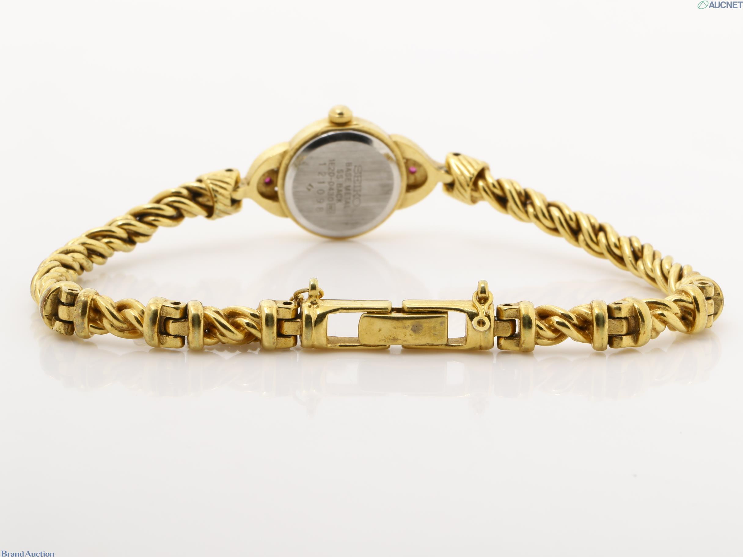 Orologio da donna Seiko color oro visto dal retro: fondello in acciaio, pietre rosse sulle anse, bracciale a catena
