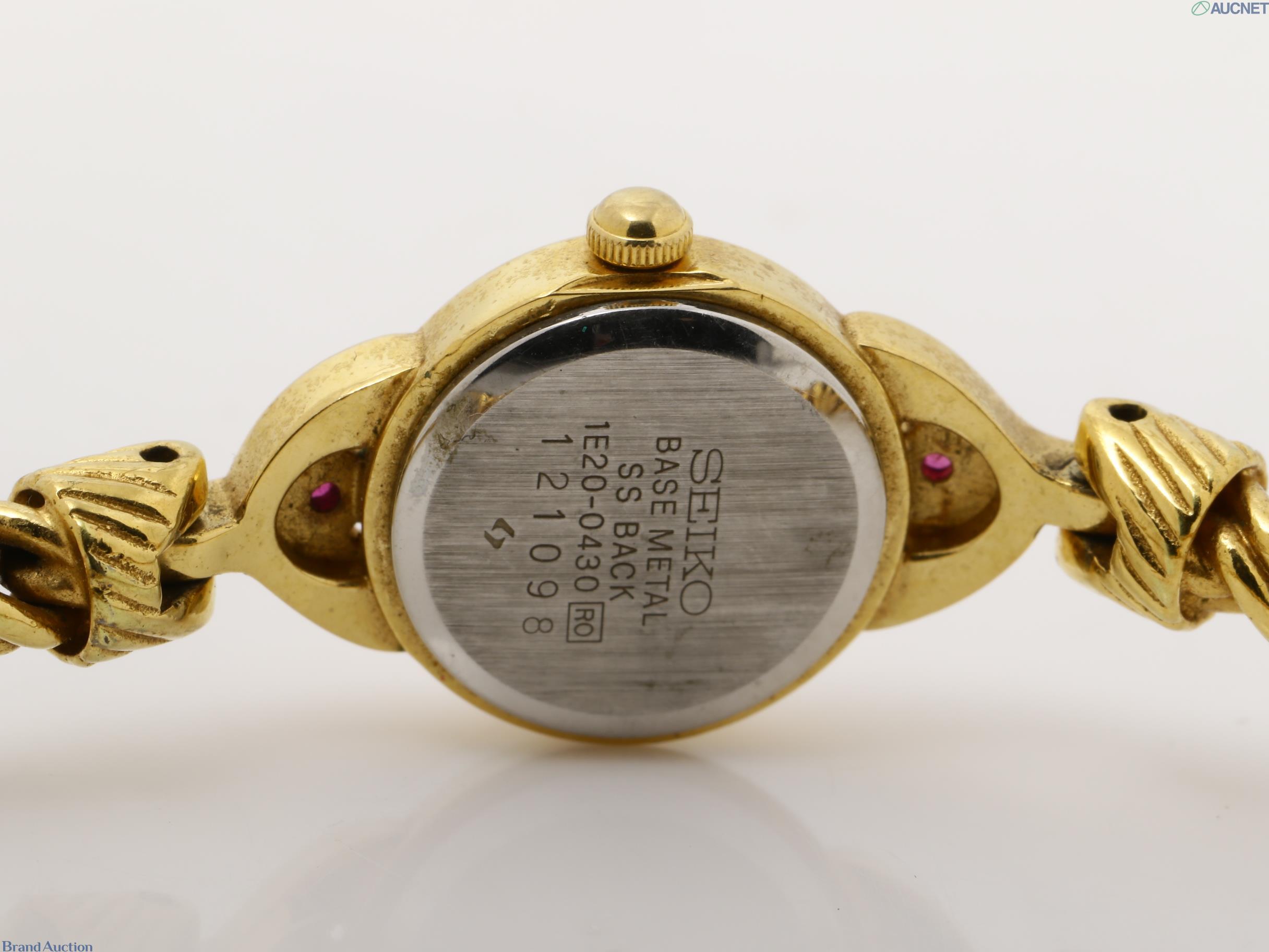 Orologio da donna Seiko color oro visto dal retro: fondello in acciaio, pietre rosse sulle anse, bracciale a catena — vista 4