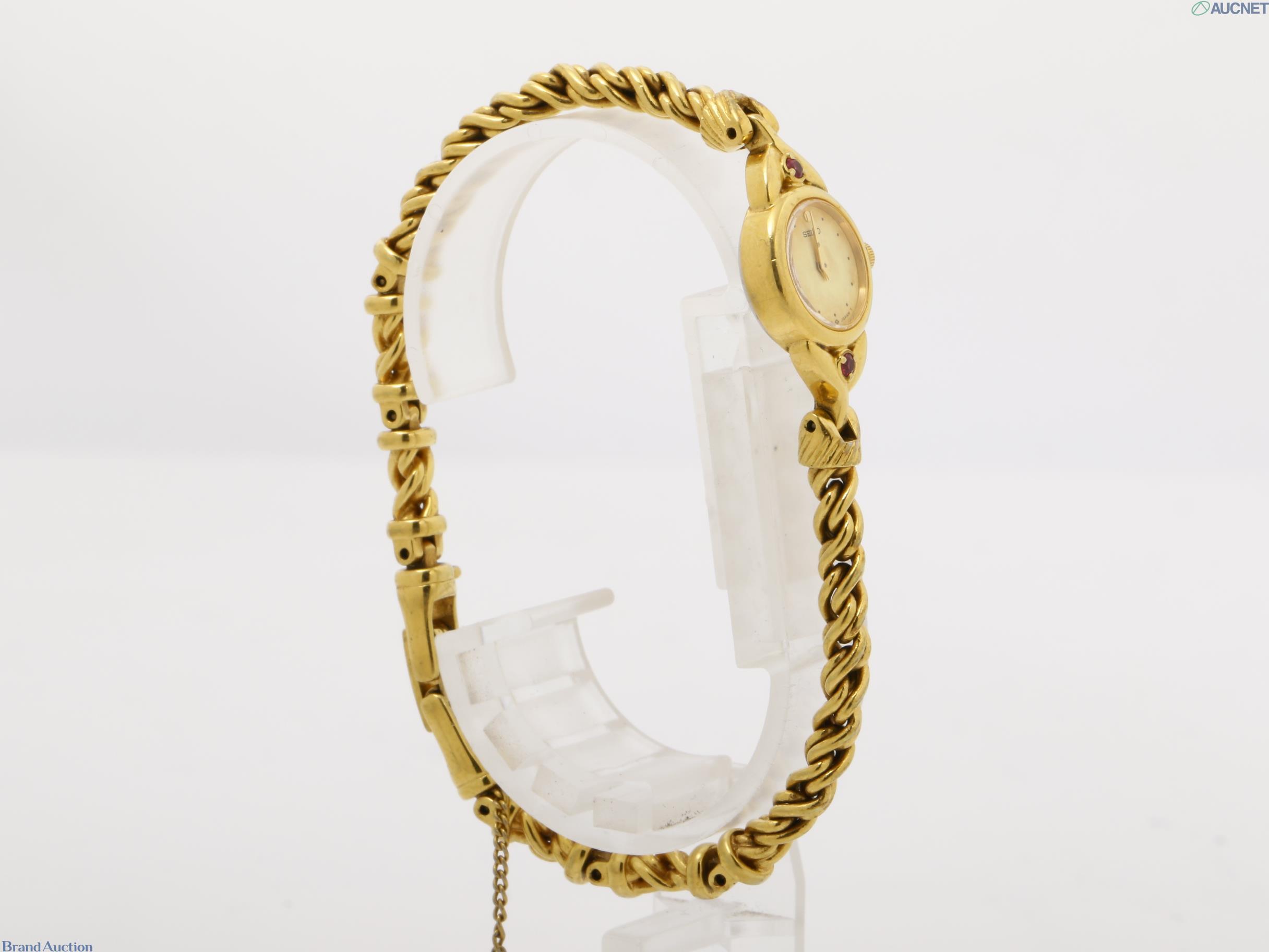 Orologio da donna Seiko color oro visto dal retro: fondello in acciaio, pietre rosse sulle anse, bracciale a catena — vista 8
