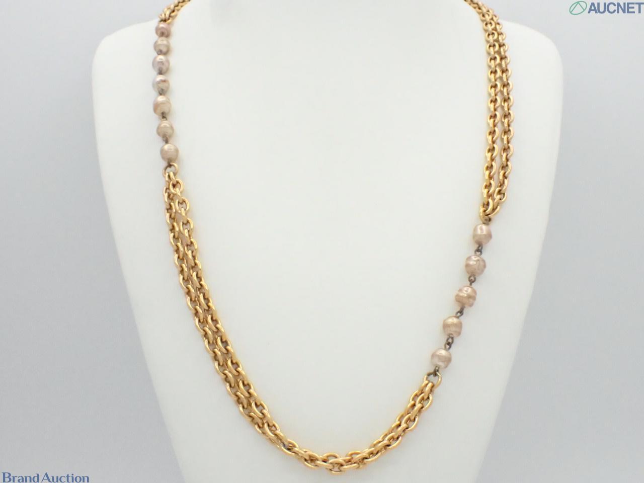 Collana lunga Chanel a catena color oro, tratti a doppia fila e perle finte a intervalli, su busto espositivo