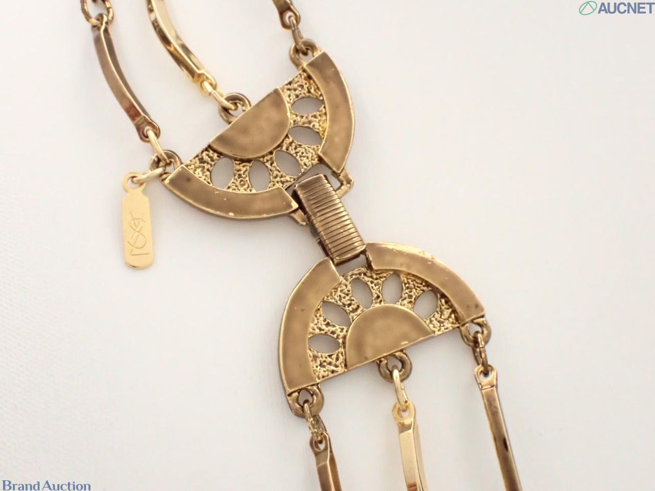 Collana Yves Saint Laurent a tre fili di barrette curve in metallo dorato, esposta su busto bianco su fondo neutro. — vista 2
