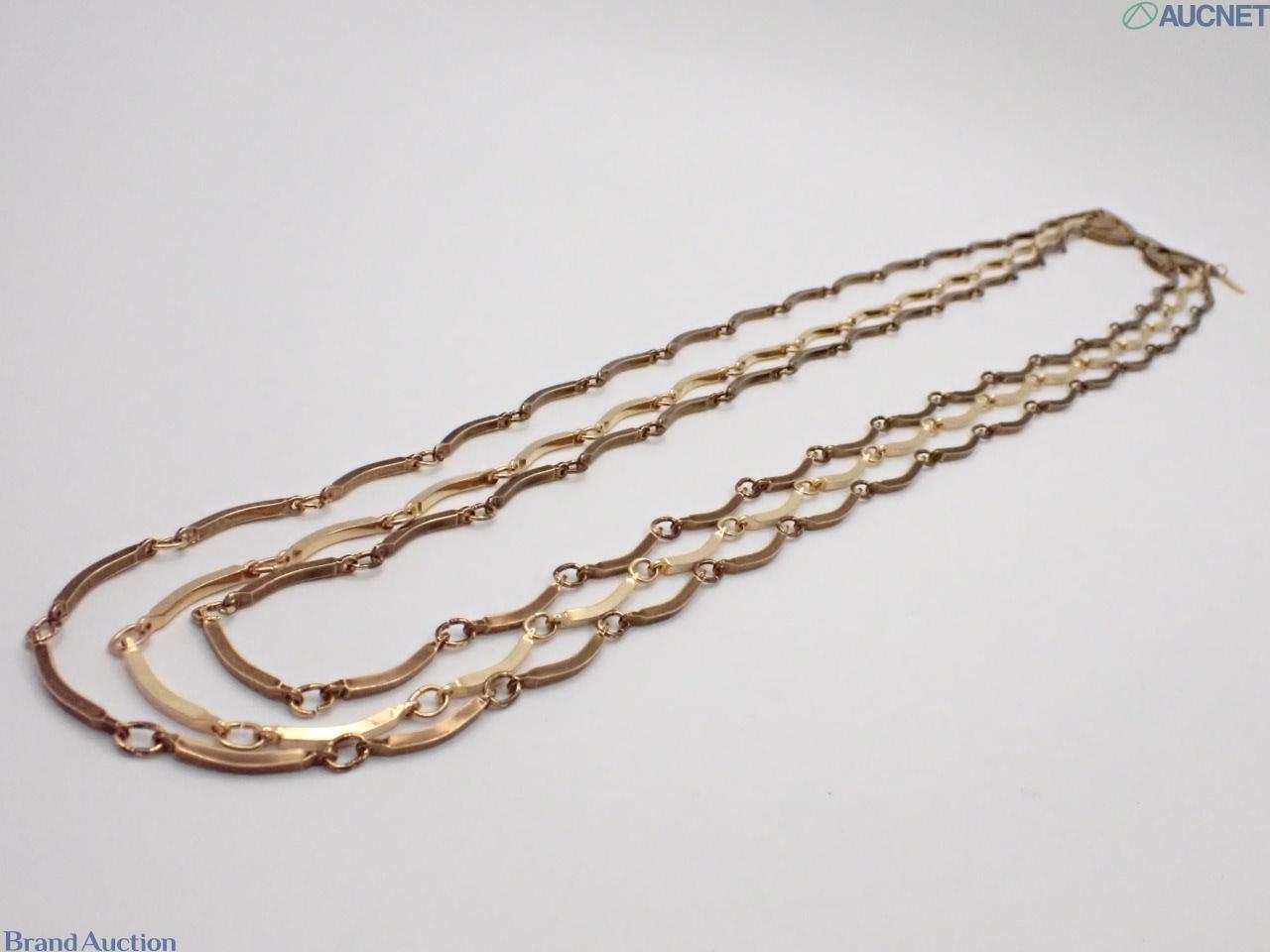 Collana Yves Saint Laurent a tre fili di barrette curve in metallo dorato, esposta su busto bianco su fondo neutro. — vista 3