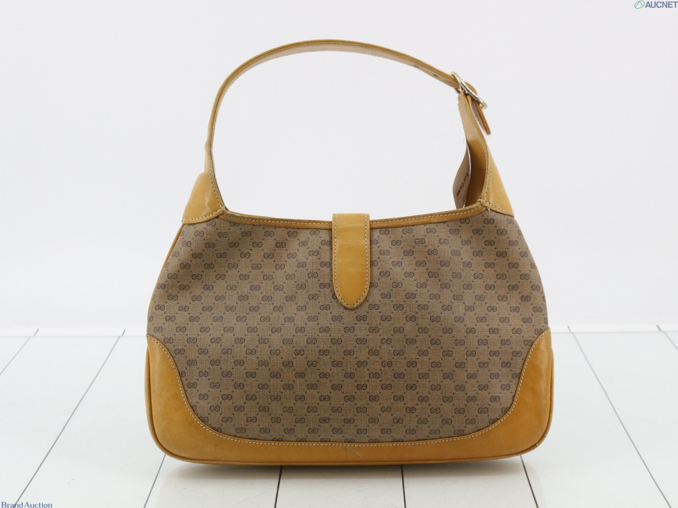 Borsa Gucci con micro motivo GG su fondo beige, finiture color miele e chiusura a pistone dorata, vista frontale — vista 2