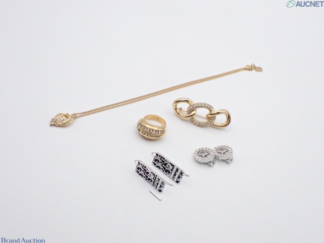 Cinque pezzi Christian Dior: collana, anello e spilla dorati con strass, orecchini pendenti a monogramma e orecchini a clip.