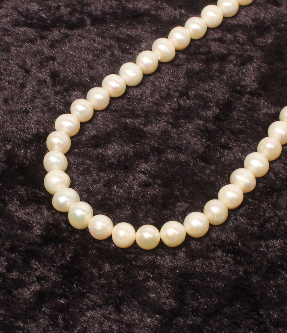 Collana a filo unico di perle d'acqua dolce chiare con chiusura a vite argentata, su velluto scuro