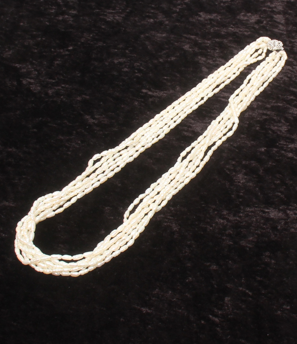 Collana a più fili di perline bianche a chicco di riso su velluto scuro, con fermaglio tondo lavorato a foglie color argento. — vista 2