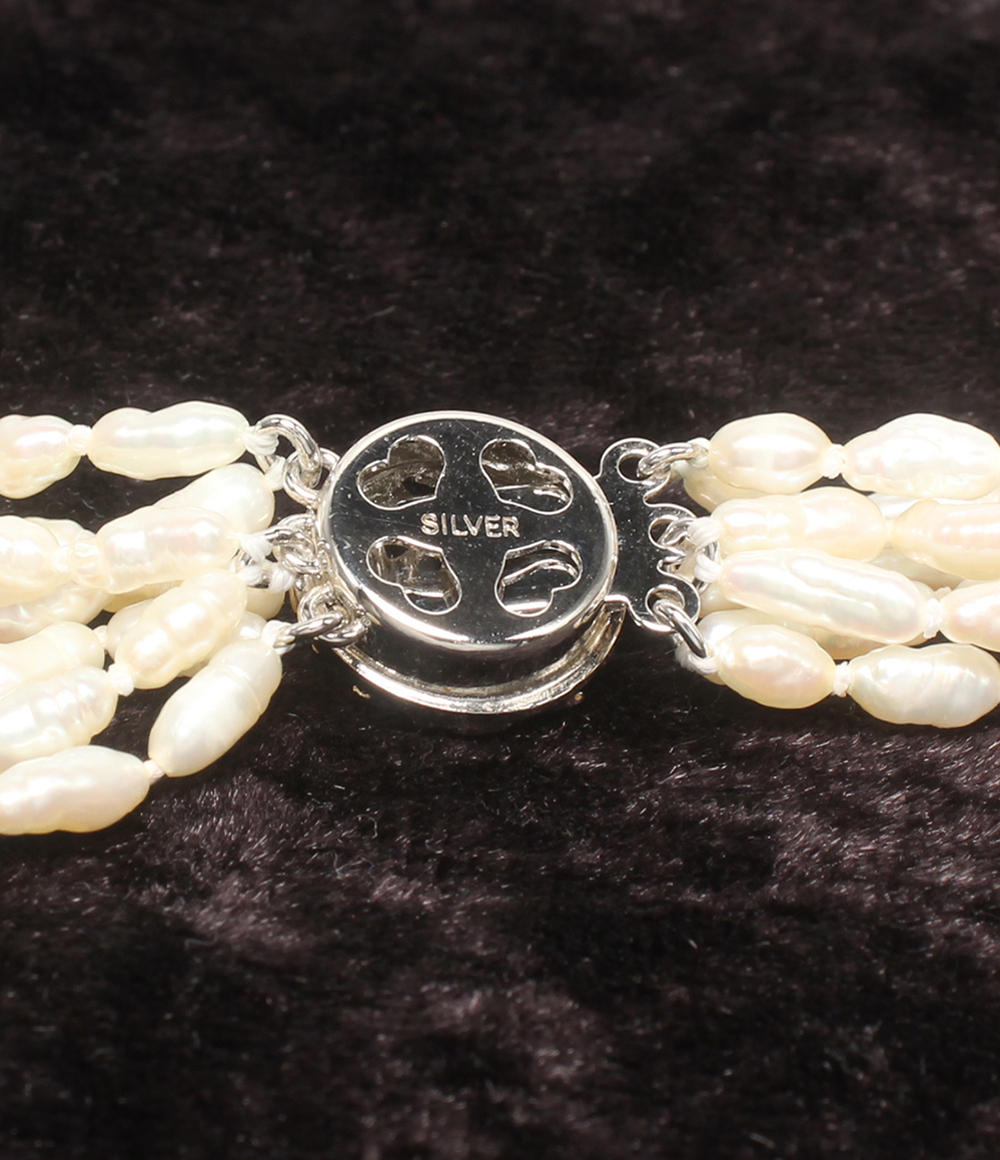 Collana a più fili di perline bianche a chicco di riso su velluto scuro, con fermaglio tondo lavorato a foglie color argento. — vista 4