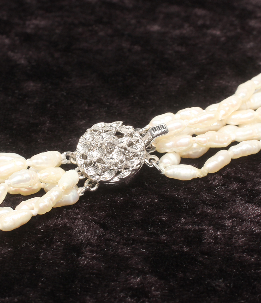 Collana a più fili di perline bianche a chicco di riso su velluto scuro, con fermaglio tondo lavorato a foglie color argento. — vista 5