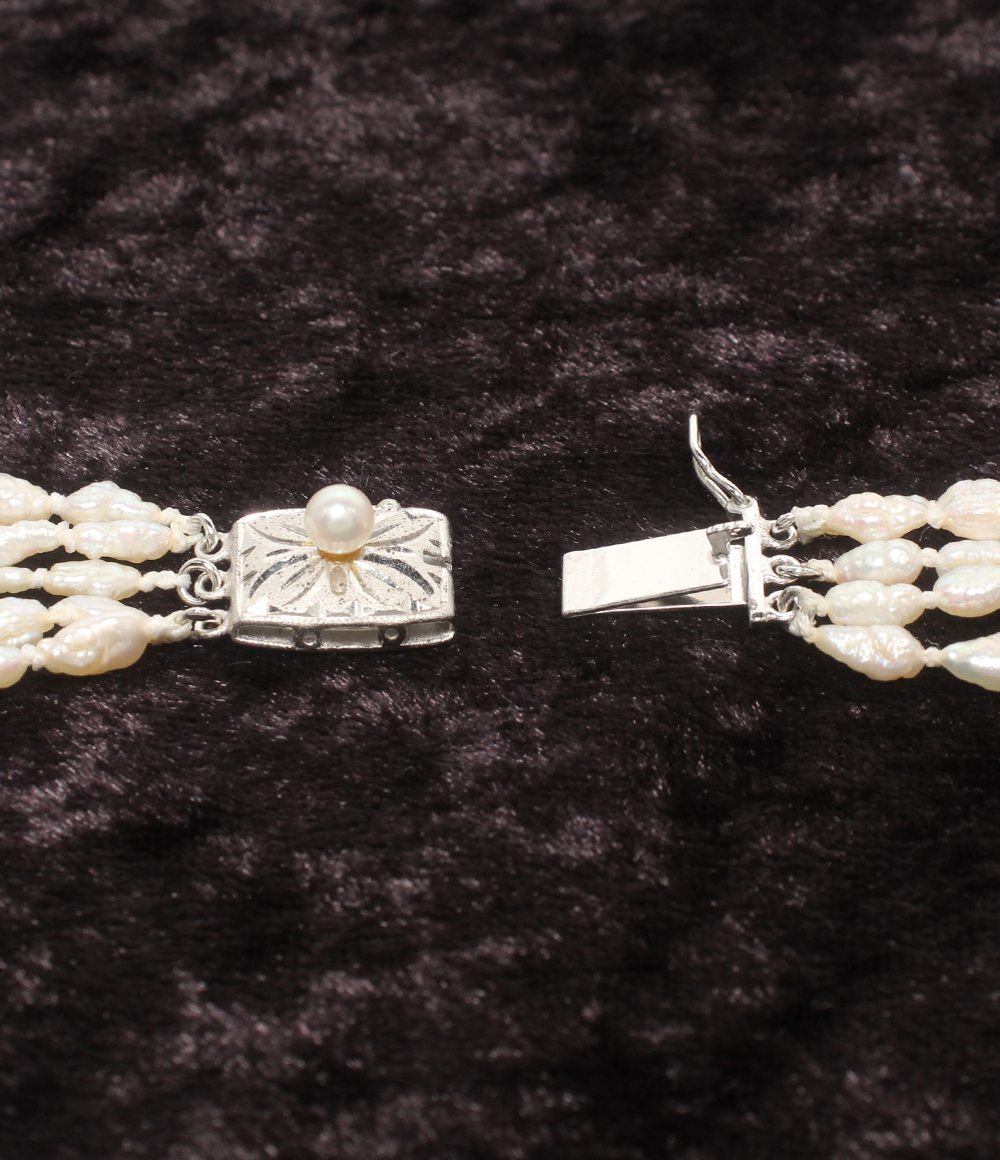 Collana lunga a più fili di perline bianche a chicco di riso, con fermaglio rettangolare inciso e una piccola perla. — vista 3