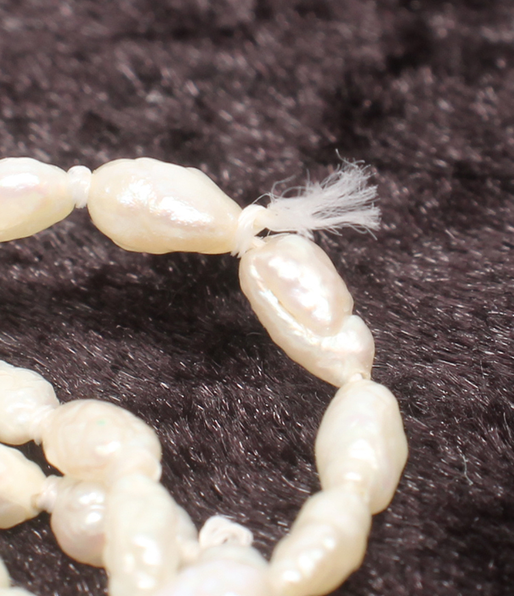 Collana lunga a più fili di perline bianche a chicco di riso, con fermaglio rettangolare inciso e una piccola perla. — vista 5