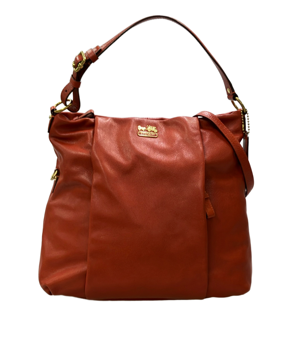 Borsa a spalla Coach in pelle color mattone, morbida, con manico regolabile a fibbia dorata e targhetta con la carrozza.
