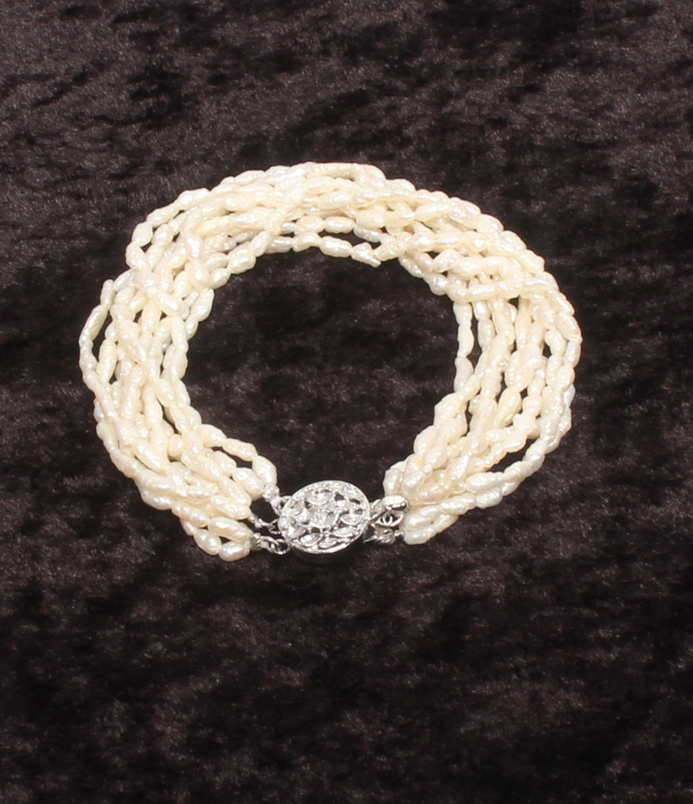 Bracciale a più fili di perline avorio a chicco di riso, con fermaglio rotondo traforato in argento, su velluto scuro. — vista 2