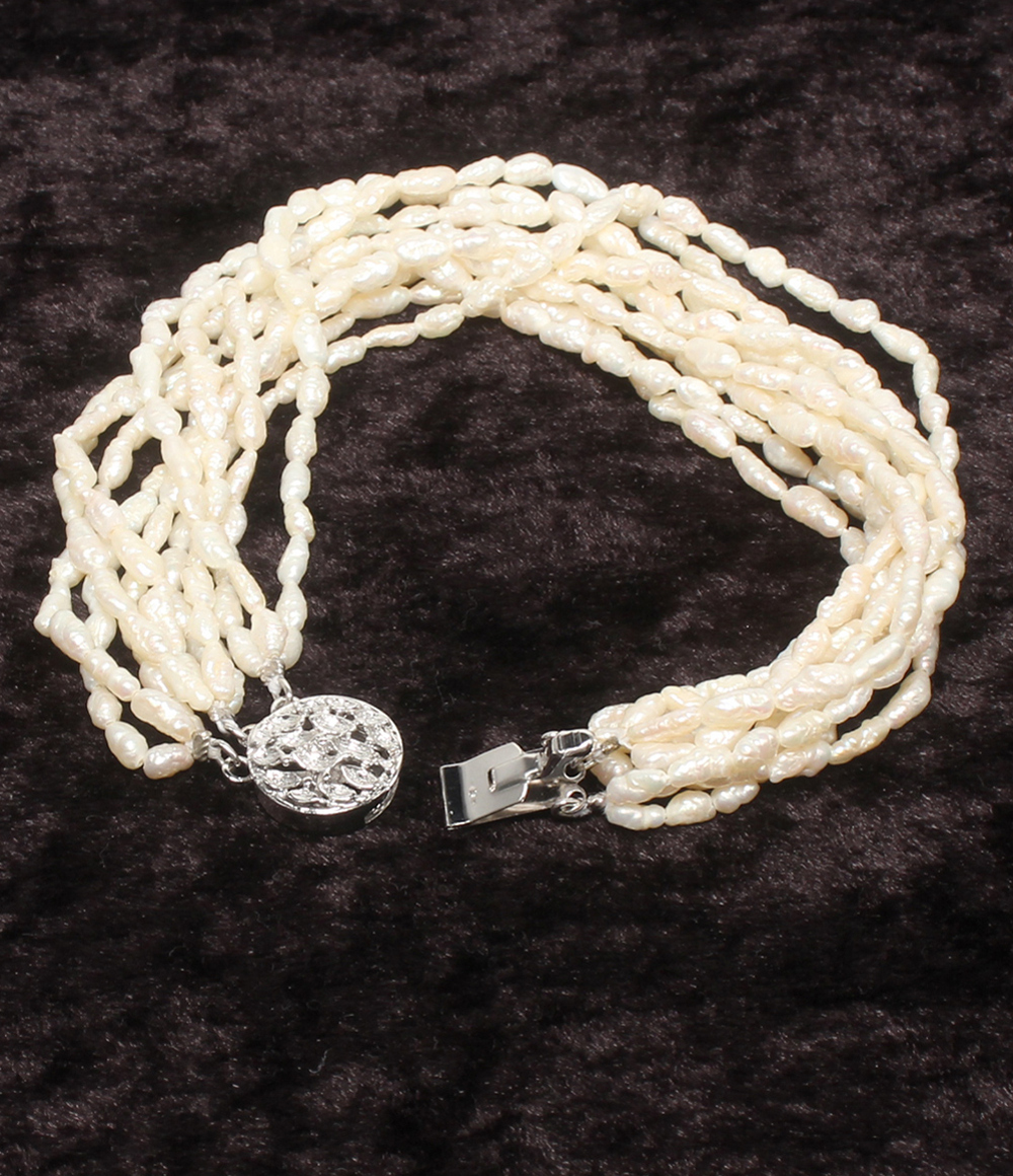 Bracciale a più fili di perline avorio a chicco di riso, con fermaglio rotondo traforato in argento, su velluto scuro. — vista 3