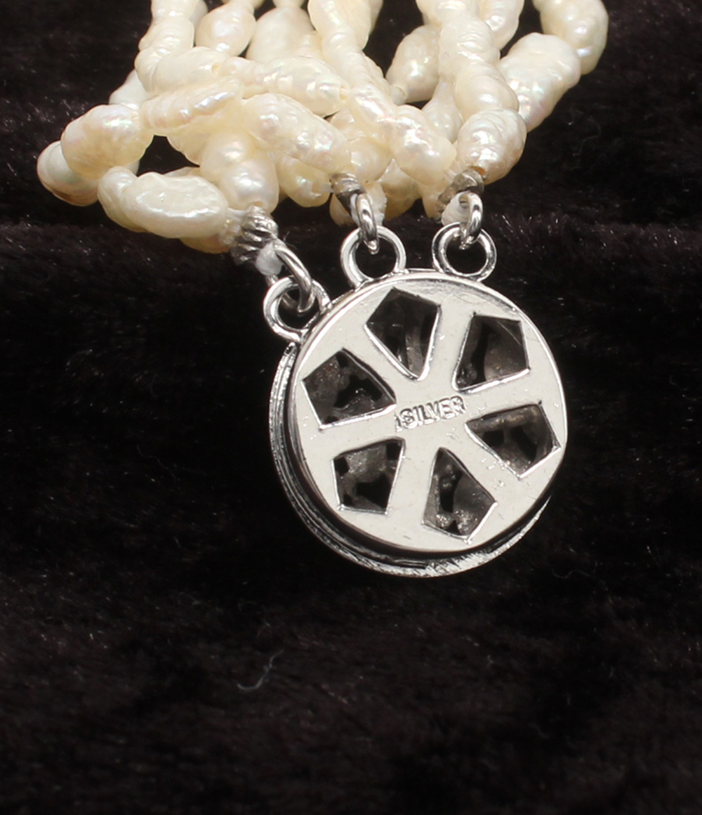Bracciale a più fili di perline avorio a chicco di riso, con fermaglio rotondo traforato in argento, su velluto scuro. — vista 4