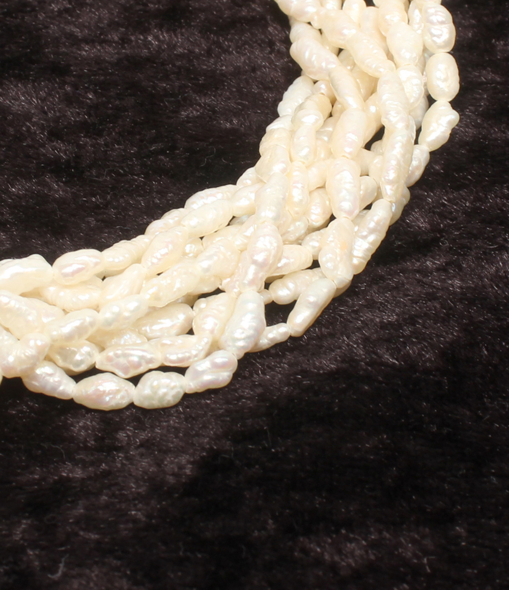 Bracciale a più fili di perline avorio a chicco di riso, con fermaglio rotondo traforato in argento, su velluto scuro. — vista 6