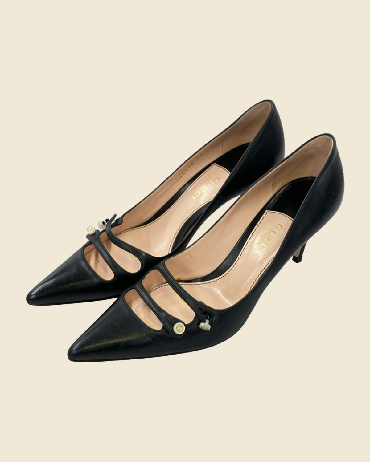 Décolleté Gucci nere a punta con tacco sottile e due cinturini sul collo del piede, chiusi da bottoncini color avorio.