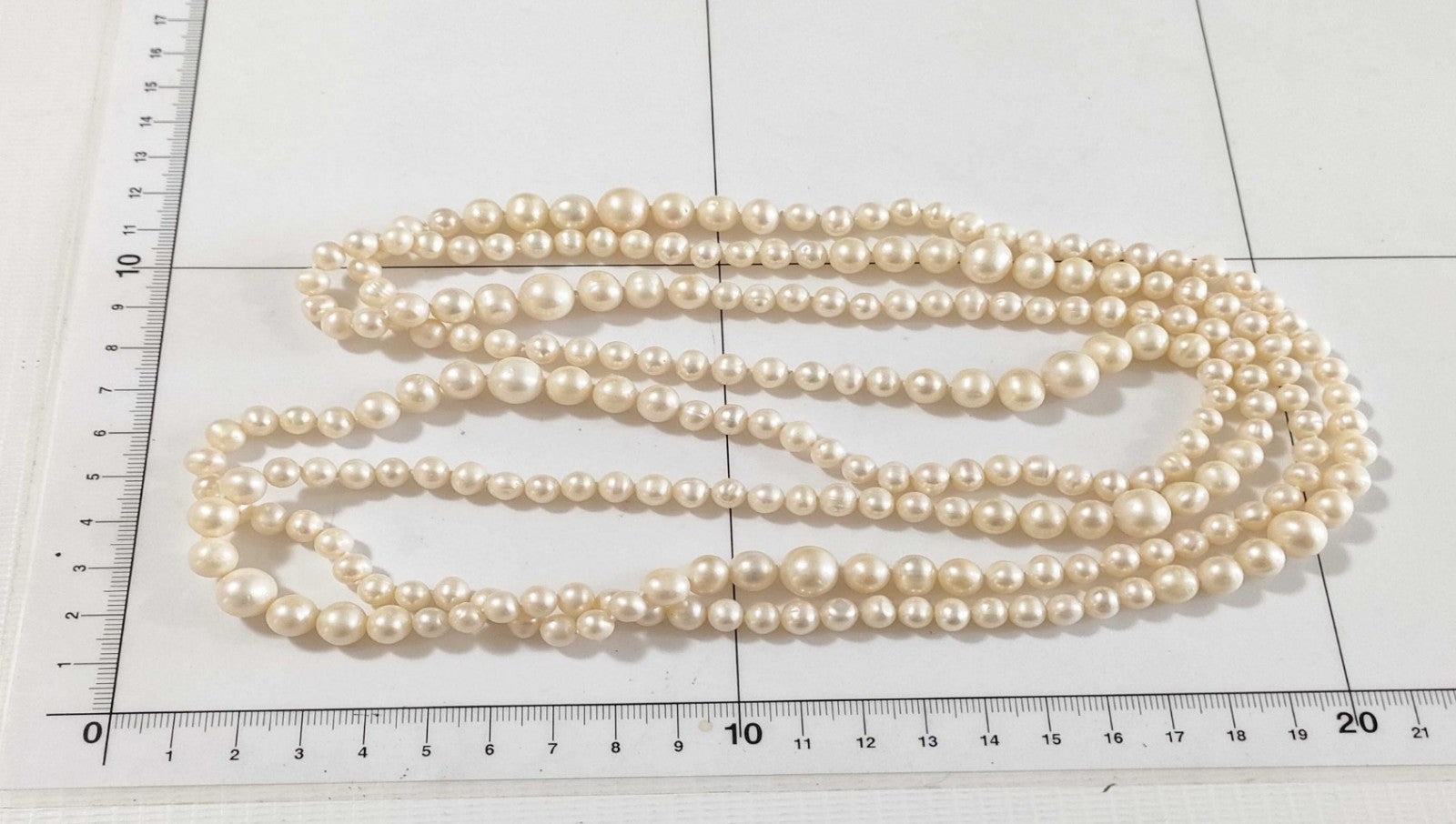 Collana lunga di perle bianche di misura alternata, indossata a doppio giro su un abito bianco a coste — vista 2