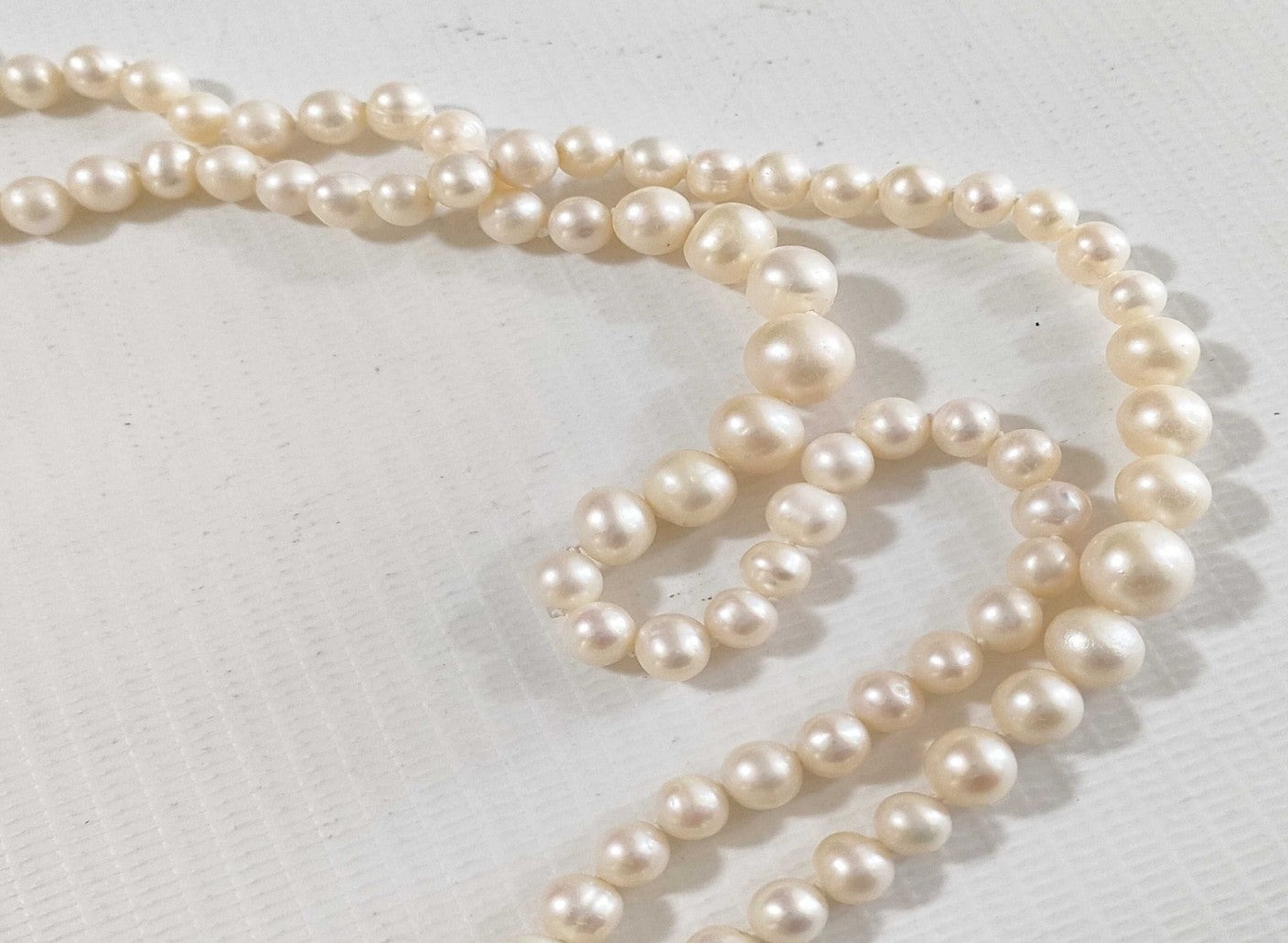 Collana lunga di perle bianche di misura alternata, indossata a doppio giro su un abito bianco a coste — vista 11