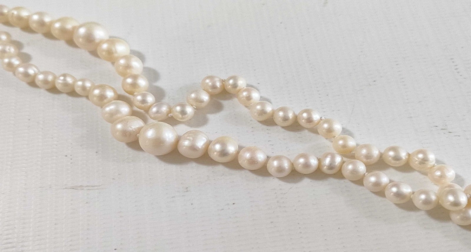 Collana lunga di perle bianche di misura alternata, indossata a doppio giro su un abito bianco a coste — vista 12