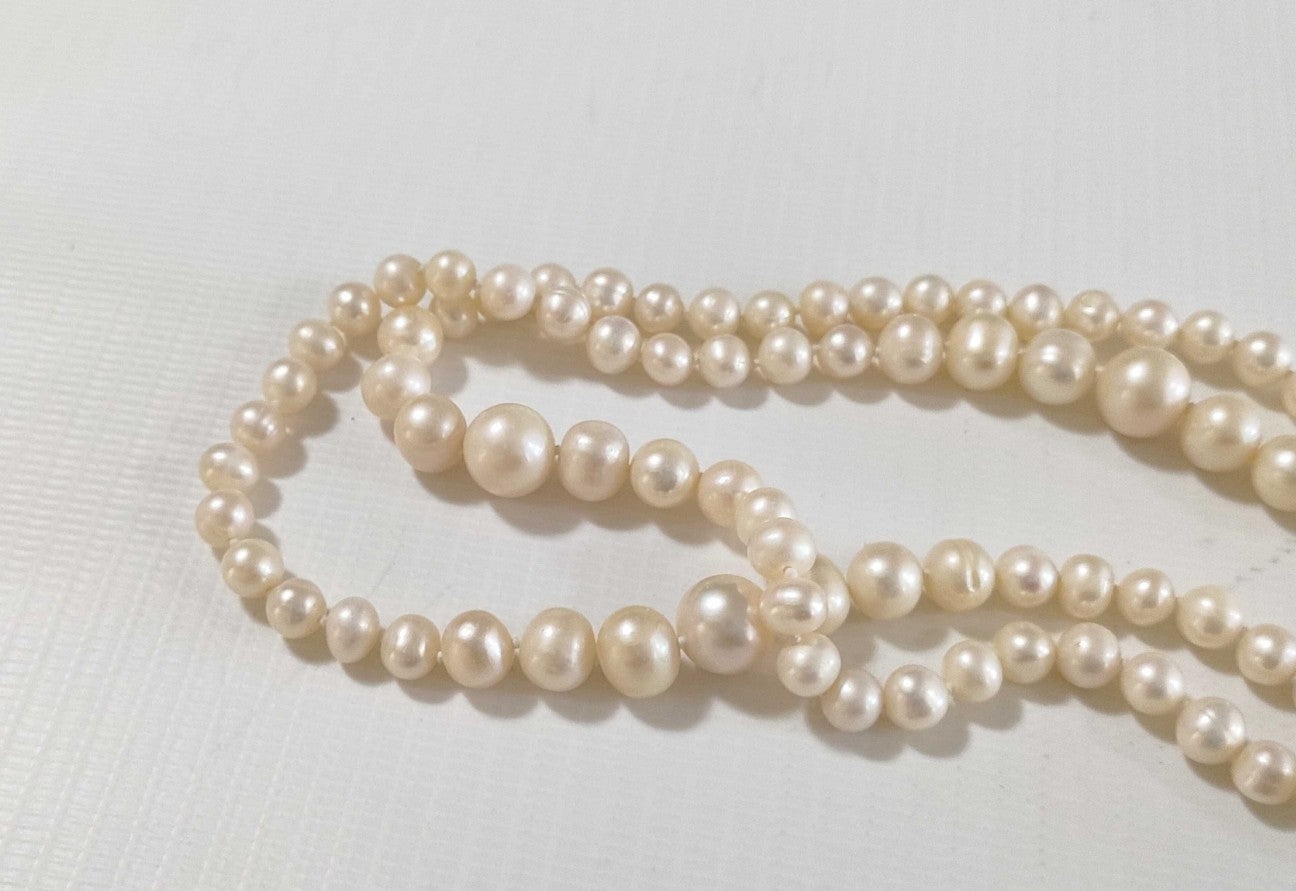Collana lunga di perle bianche di misura alternata, indossata a doppio giro su un abito bianco a coste — vista 7