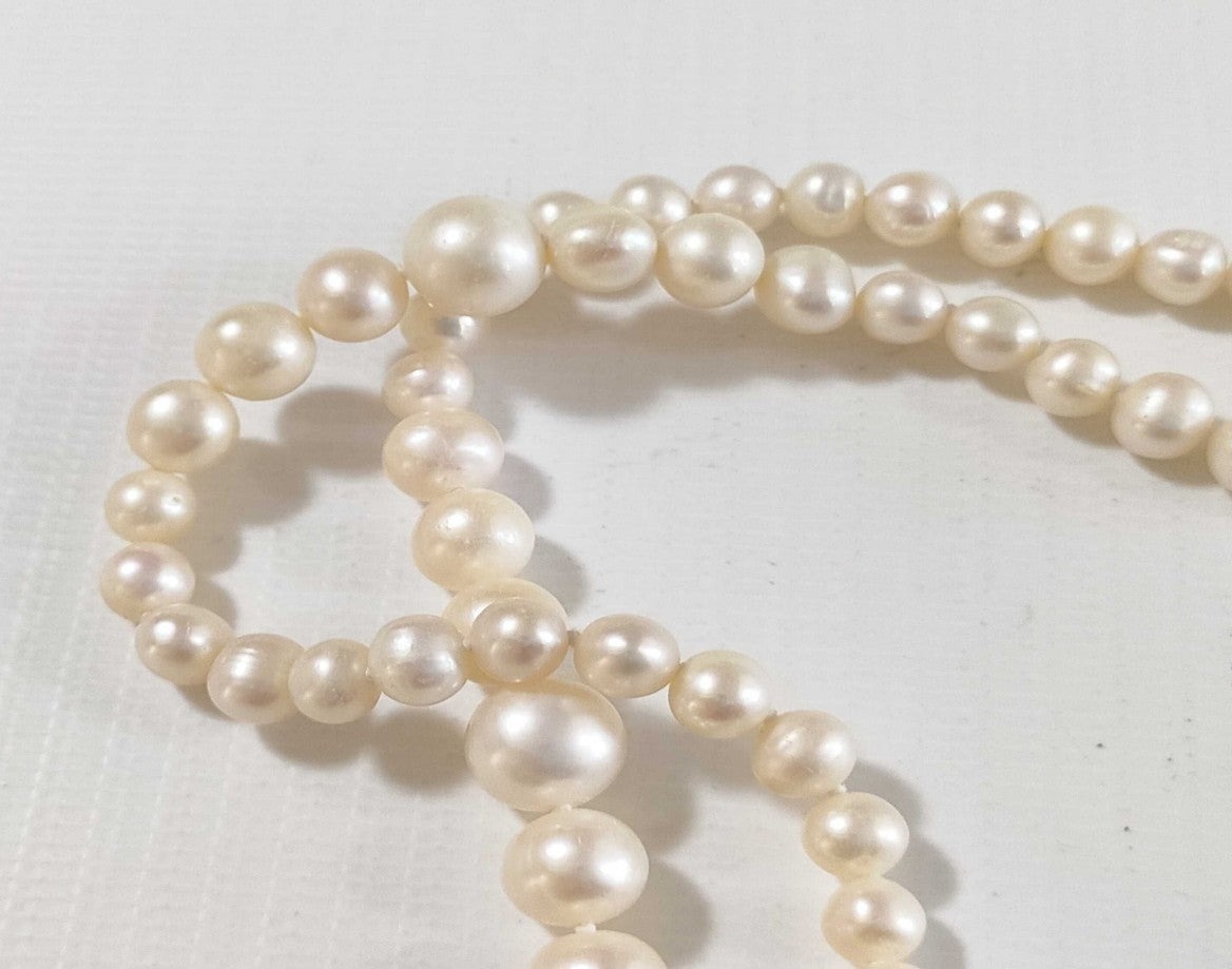 Collana lunga di perle bianche di misura alternata, indossata a doppio giro su un abito bianco a coste — vista 8