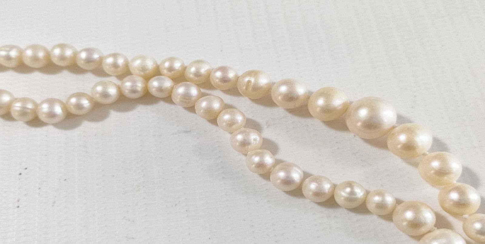 Collana lunga di perle bianche di misura alternata, indossata a doppio giro su un abito bianco a coste — vista 9