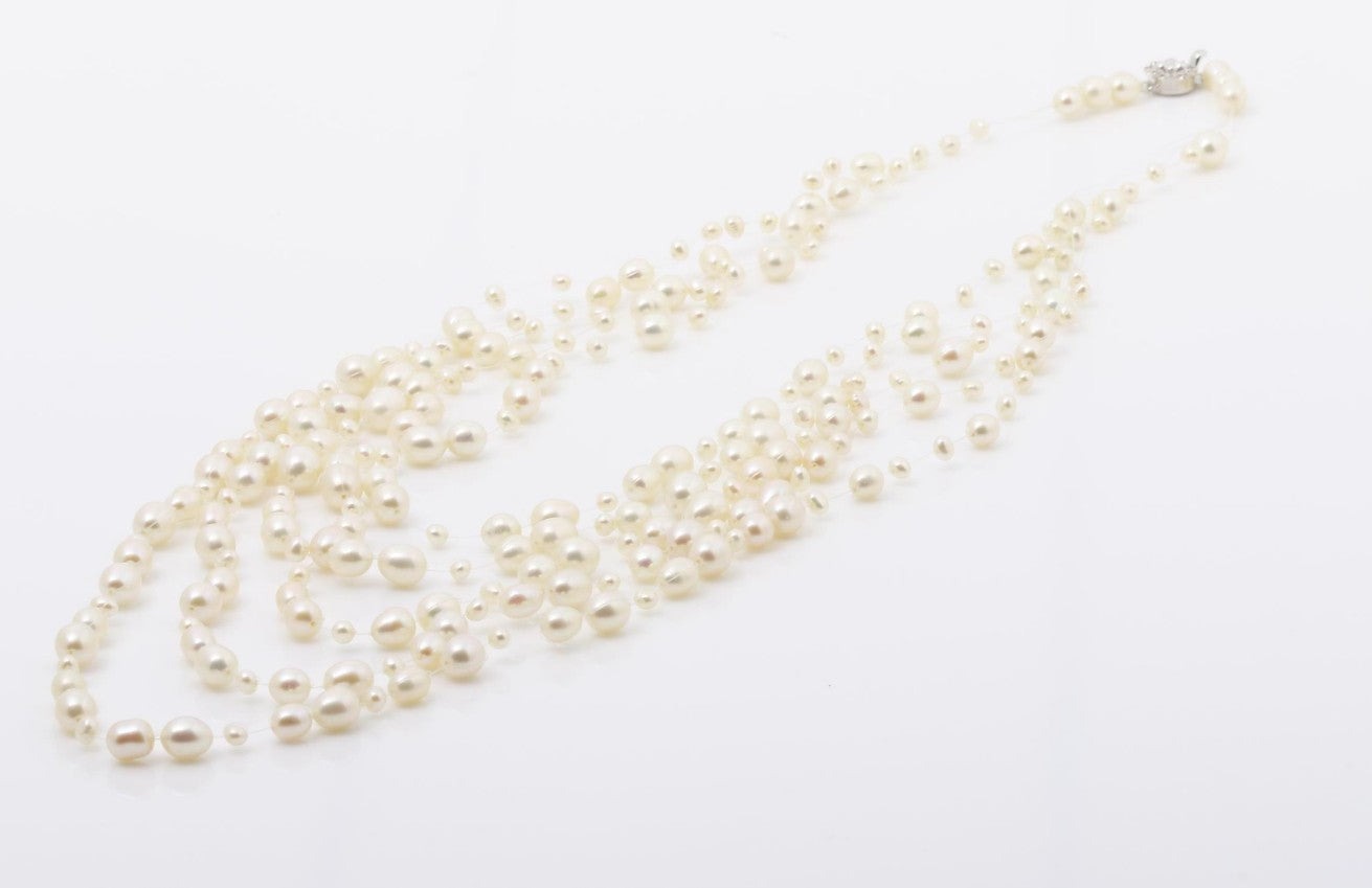 Collana a cinque fili di perle bianche d'acqua dolce su filo trasparente, a cascata, indossata su un maglione nero — vista 5
