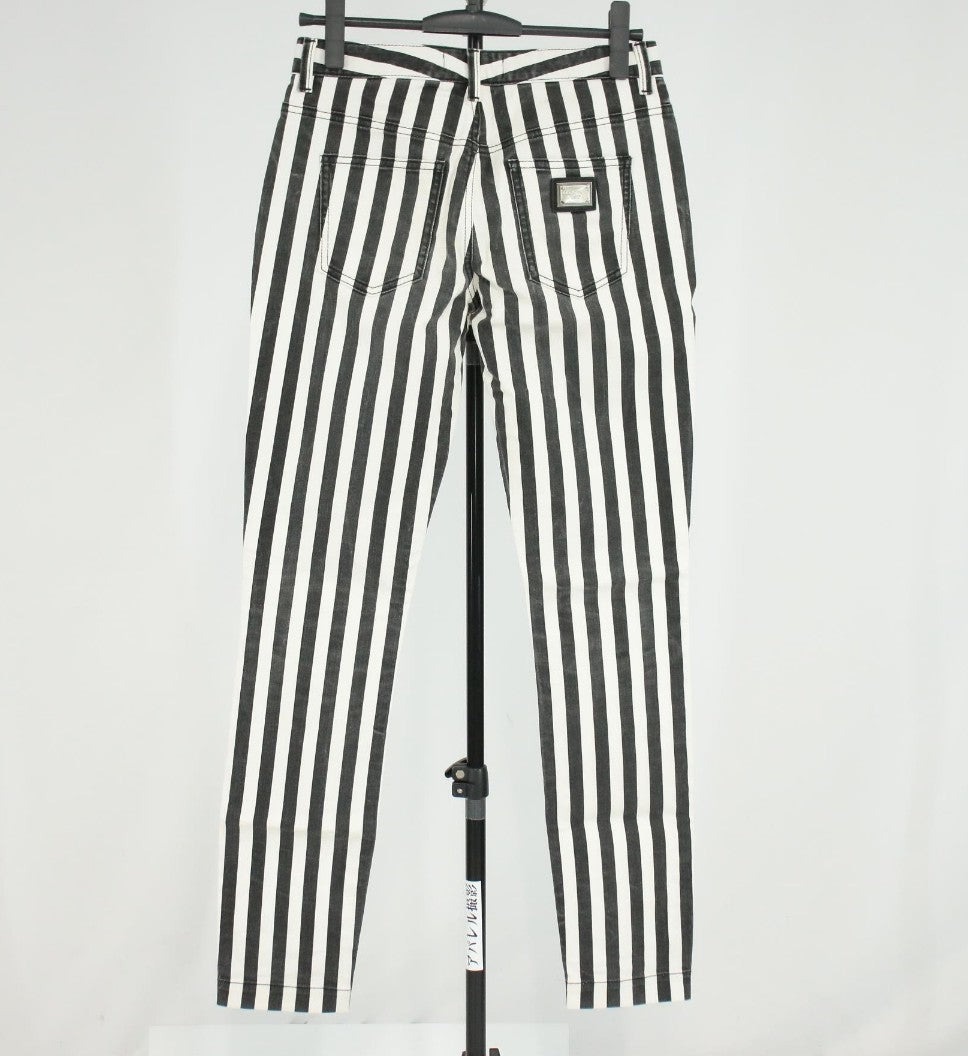 Pantaloni aderenti Dolce&Gabbana a righe verticali nere e bianche, indossati, con bottone in vita e tasche anteriori.