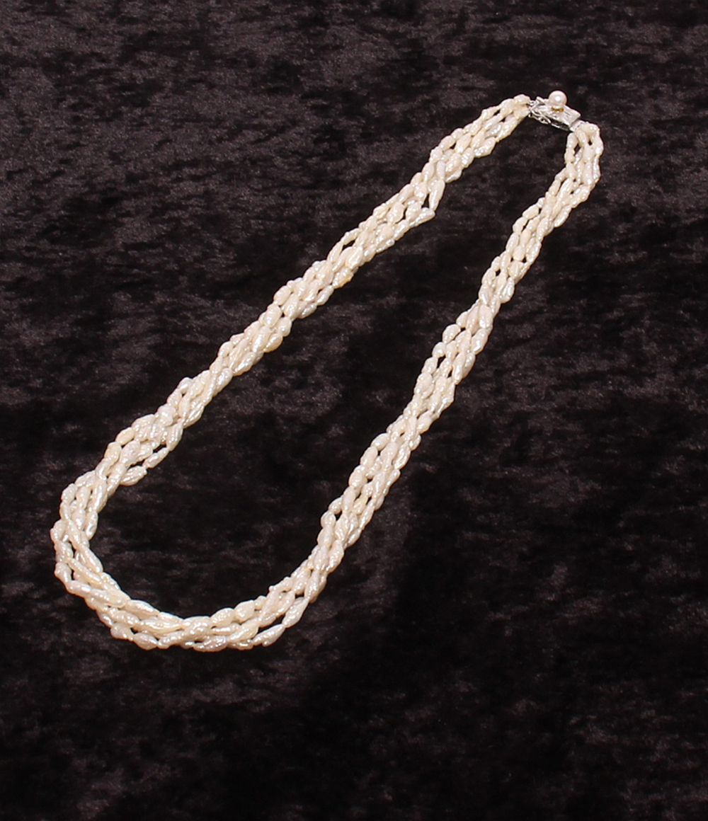 Collana a più fili di piccole perle bianche irregolari, intrecciati fra loro, posata su velluto scuro. — vista 2