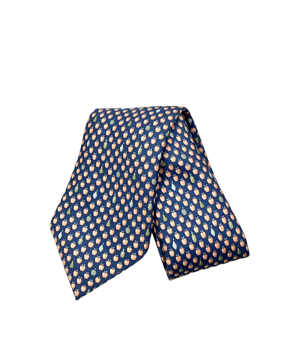Cravatta Hermès in seta blu a piccole mele color pesca, con pere e ananas sparsi, ripiegata su fondo bianco