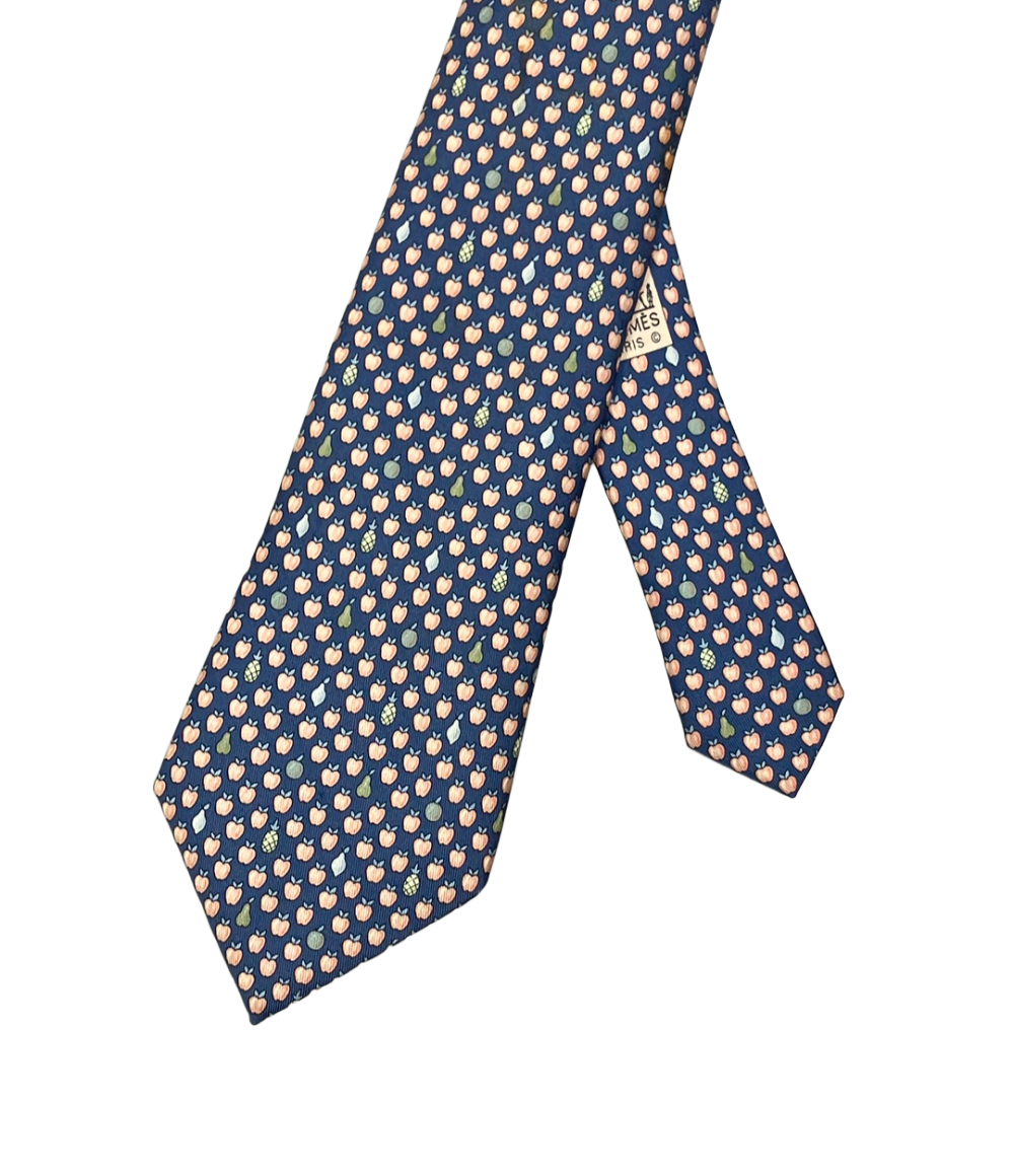 Cravatta Hermès in seta blu a piccole mele color pesca, con pere e ananas sparsi, ripiegata su fondo bianco — vista 2